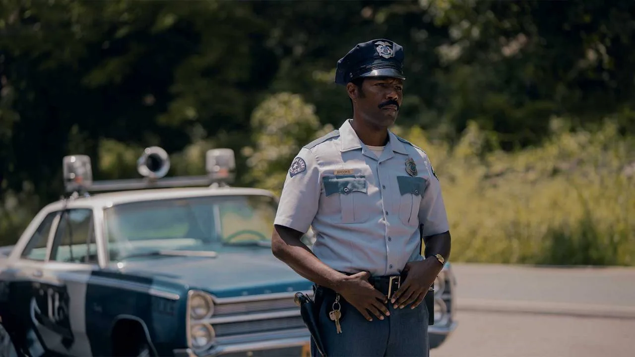 Levon stands beside his police car