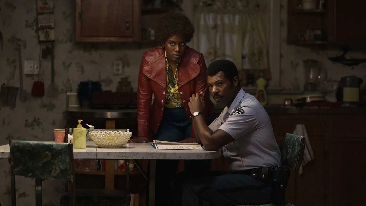 Briana and Levon look toward someone across the kitchen table